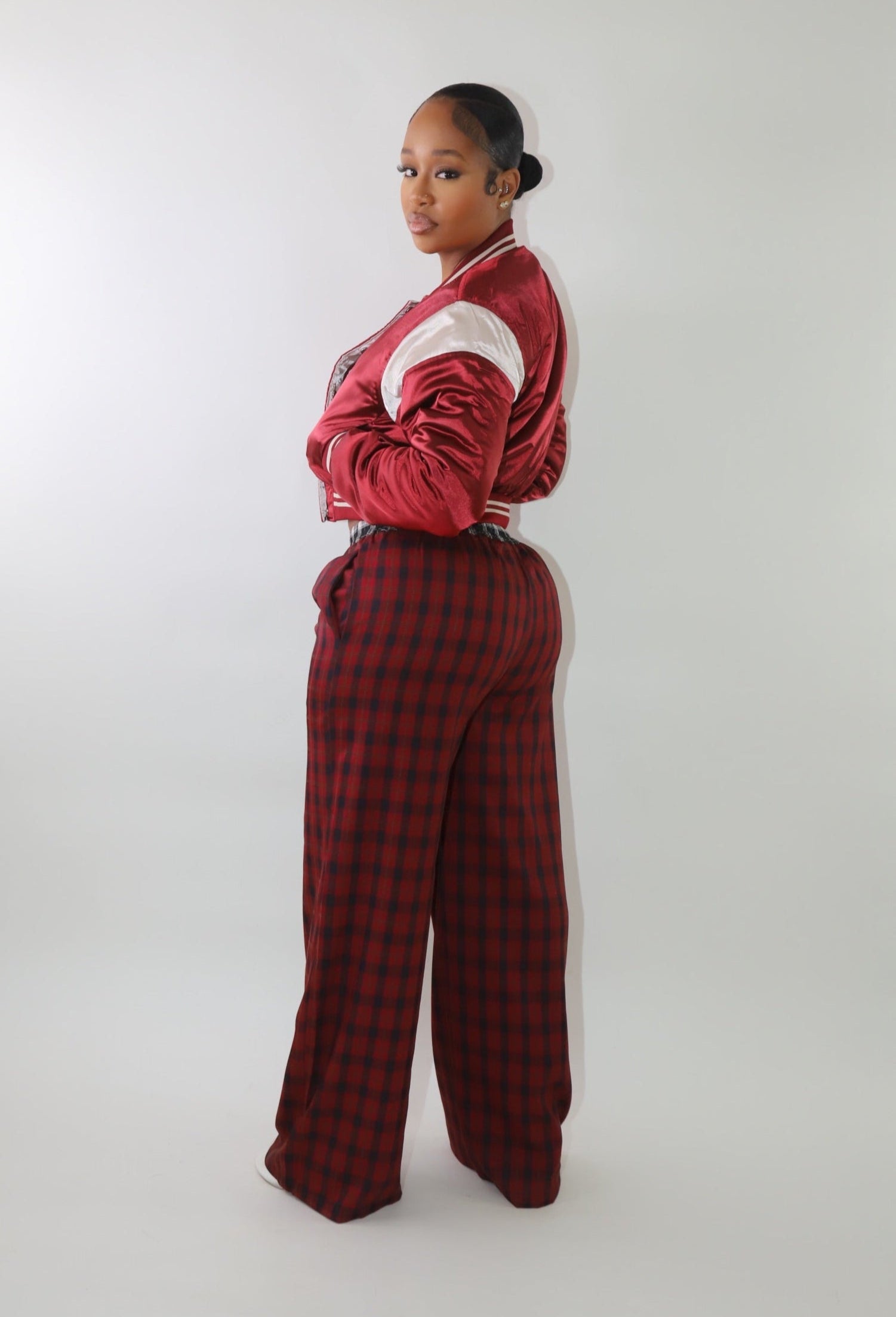 A woman wearing high-waisted red and black plaid wide-leg pants with a relaxed fit and contrasting black-and-white plaid waistband detail. The pants have an effortless oversized silhouette, making them perfect for cozy yet stylish wear.