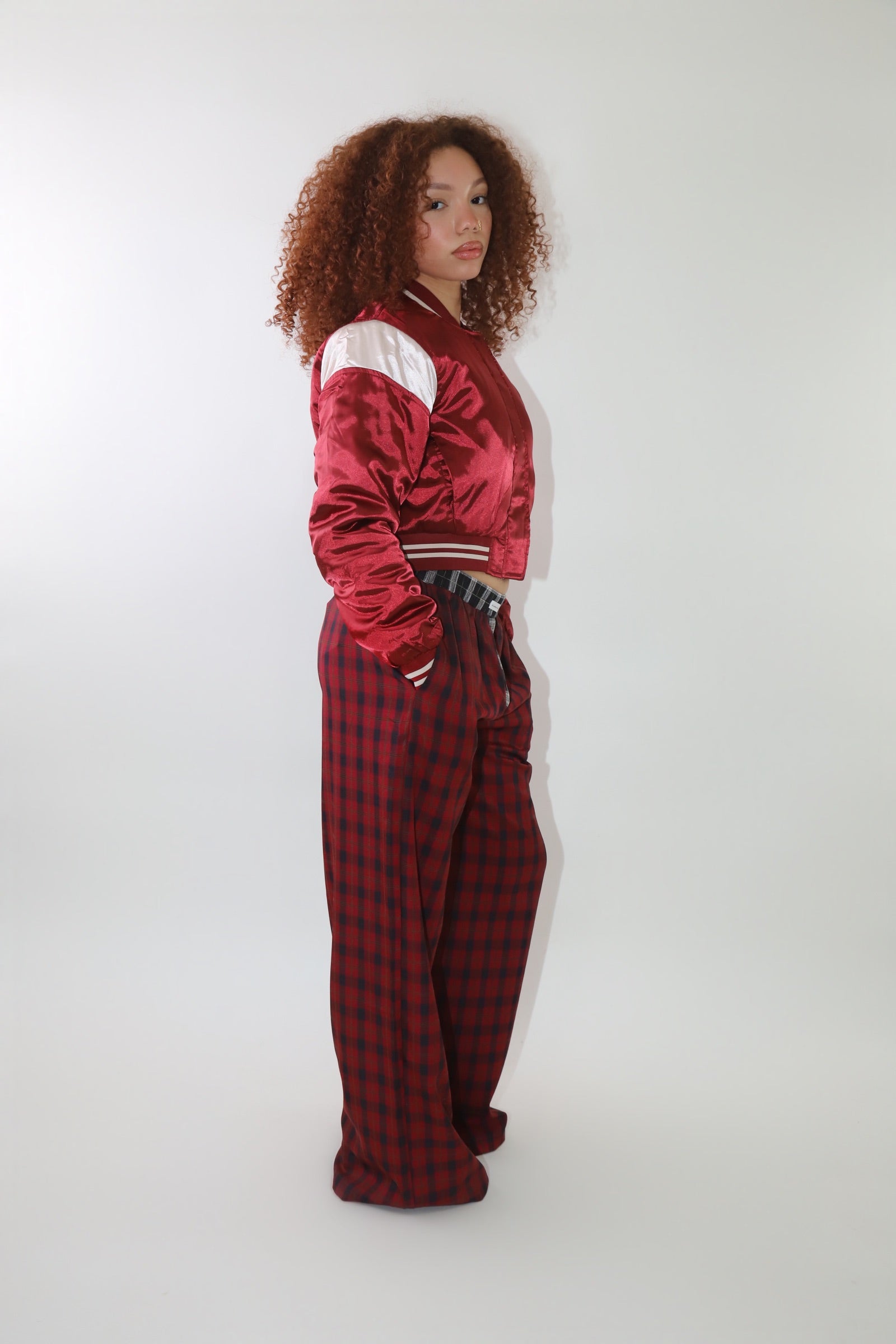 A woman wearing high-waisted red and black plaid wide-leg pants with a relaxed fit and contrasting black-and-white plaid waistband detail. The pants have an effortless oversized silhouette, making them perfect for cozy yet stylish wear.